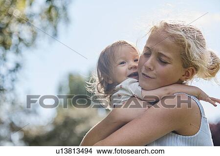 Girl hugging baby sister affectionately View Large Photo Image Picture - Girl hugging baby sister affectionately. Fotosearch