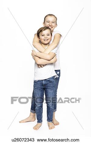 Stock Image - Girl hugging brother from behind, white background. Fotosearch