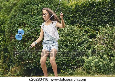 Stock Photograph - Girl playing with diabolo in garden. Fotosearch