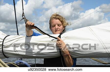 Stock Photo - Girl prepares sails on flat-bottom traditional sailing ship, Sneekermeer, Friesland, Netherlands. Fotosearch