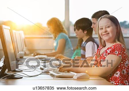 Stock Photography - Girl with Down syndrome using computer at school. Fotosearch