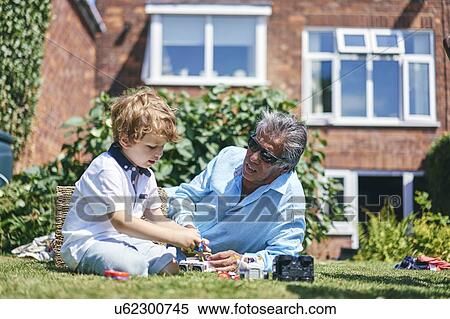 Grandfather watching grandson play on grass View Large Photo Image Stock Photography - Grandfather watching grandson play on grass. Fotosearch