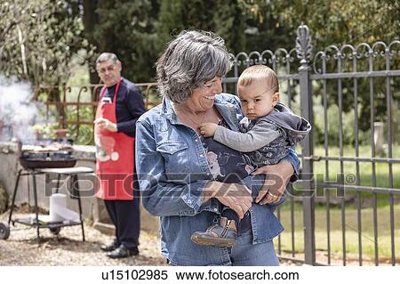 Grandmother carrying baby boy at family BBQ gathering, Florence, Italy View Large Photo Image Stock Photography - Grandmother carrying baby boy at family BBQ gathering, Florence, Italy. Fotosearch