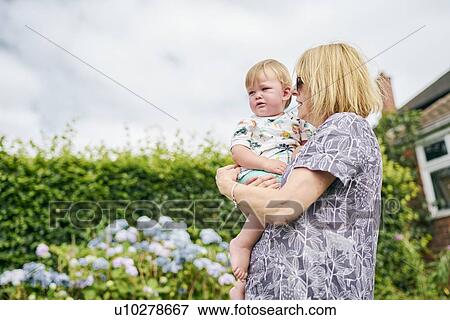 Grandmother carrying baby girl in garden View Large Photo Image Stock Photo - Grandmother carrying baby girl in garden. Fotosearch