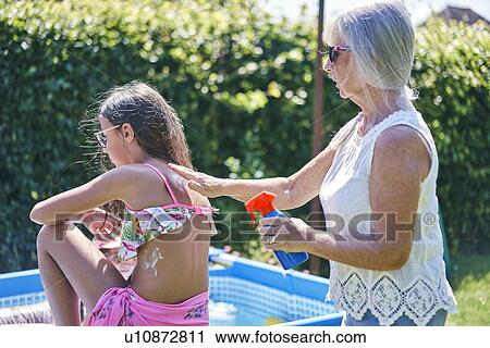 Grandmother putting sun lotion on granddaughter View Large Photo Image Stock Image - Grandmother putting sun lotion on granddaughter. Fotosearch