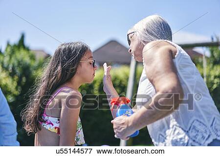 Stock Photo - Grandmother putting sun lotion on granddaughter. Fotosearch