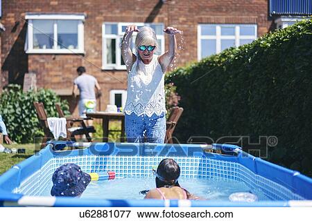 Grandmother watching grandchildren playing in pool View Large Photo Image Stock Photo - Grandmother watching grandchildren playing in pool. Fotosearch