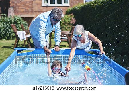 Stock Photo - Grandparents supporting granddaughter in pool. Fotosearch