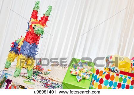 Stock Image - Group of gifts and birthday cake on table including pinata. Fotosearch