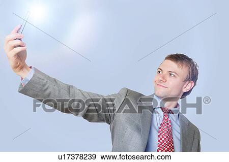 Handsome young businessman taking self-portrait photograph over blue background View Large Photo Image Stock Photo - Handsome young businessman taking self-portrait photograph over blue background. Fotosearch