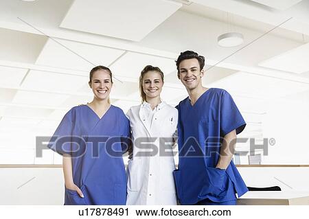 Stock Image - Happy doctor and nurses at corridor in hospital. Fotosearch