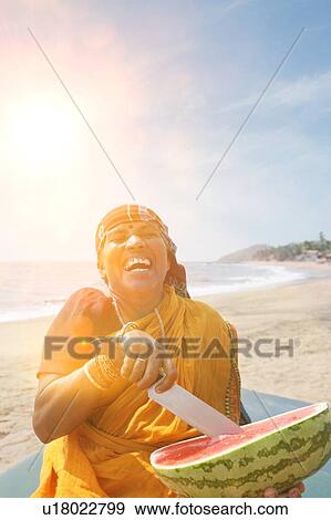 Happy mature Indian woman cutting watermelon at Vagator Beach View Large Photo Image Stock Photo - Happy mature Indian woman cutting watermelon at Vagator Beach. Fotosearch