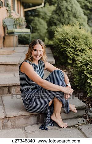 Stock Image - Happy woman sitting on garden steps. Fotosearch