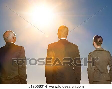 Isolated photo of Rear view of three business people looking at sun View Large Photo Image Picture - Isolated photo of Rear view of three business people looking at sun. Fotosearch