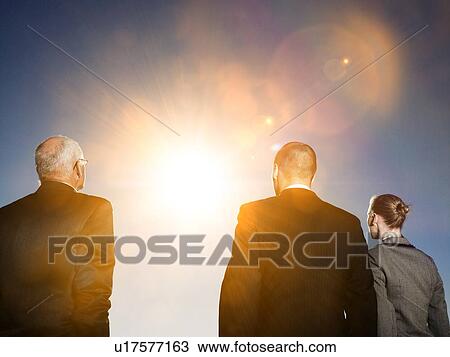 Stock Image - Isolated photo of Rear view of three business people looking at sun. Fotosearch