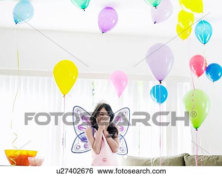 Stock Photograph - little girl at her birthday party looking at balloons. Fotosearch