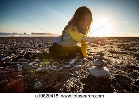 Little girl stacking wish stones, black sand beach, Reynisfjara, Iceland View Large Photo Image Stock Photography - Little girl stacking wish stones, black sand beach, Reynisfjara, Iceland. Fotosearch