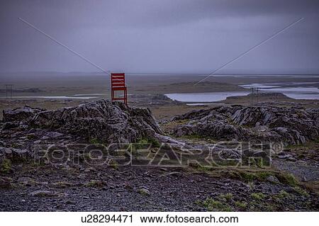 Stock Image - Lone red chair placed in middle of nowhere, Ring Road, Iceland. Fotosearch