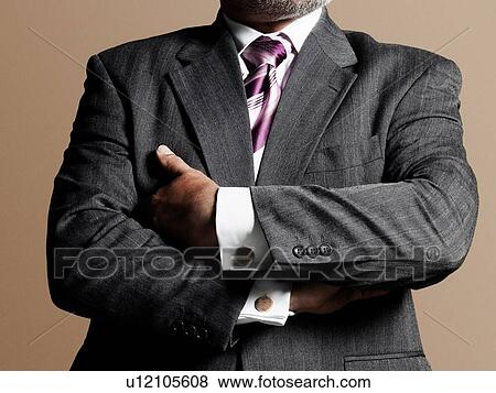 Stock Photo - Male business man in suit with arms folded. Fotosearch