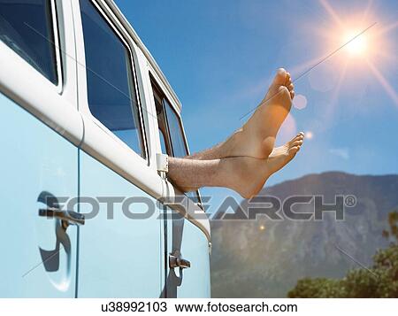 Stock Image - Male feet poking outside truck with sunshining in background. Fotosearch
