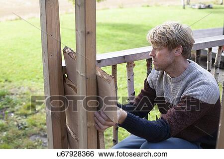Stock Photograph - Man building treehouse in garden. Fotosearch
