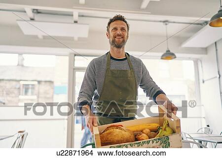 Man carrying crate of food supply into restaurant View Large Photo Image Picture - Man carrying crate of food supply into restaurant. Fotosearch