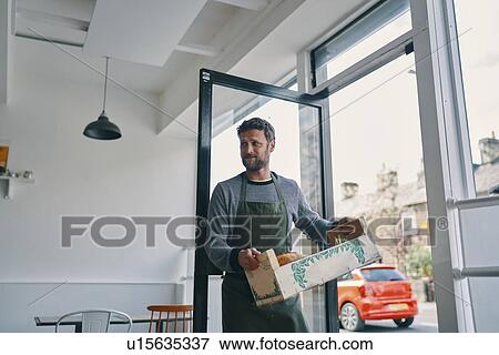 Stock Photo - Man carrying crate of food supply into restaurant. Fotosearch