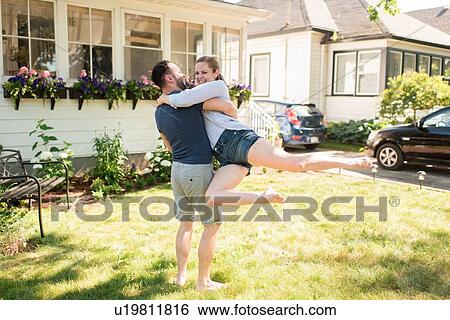Stock Photograph - Man carrying woman and swinging her in garden. Fotosearch