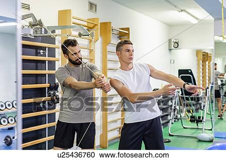 Man coaching friend in gym View Large Photo Image Stock Image - Man coaching friend in gym. Fotosearch