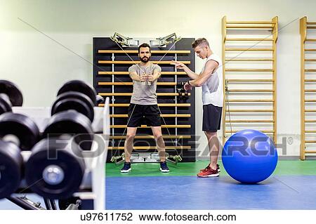 Man coaching friend in gym View Large Photo Image Stock Image - Man coaching friend in gym. Fotosearch