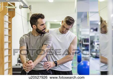 Man coaching friend in gym View Large Photo Image Stock Photograph - Man coaching friend in gym. Fotosearch