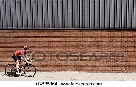 Picture - Man cycling on bicycle in city. Fotosearch