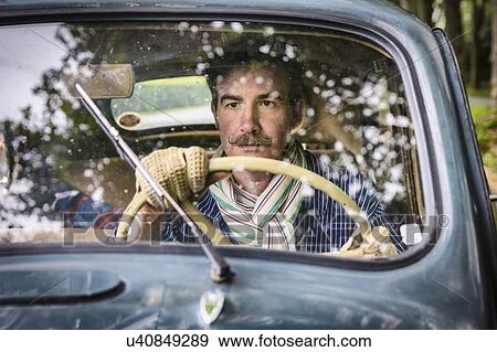 Stock Photo - Man driving vintage car on country road. Fotosearch