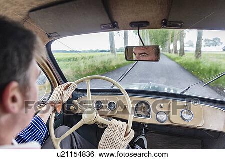 Stock Photograph - Man driving vintage car on country road. Fotosearch