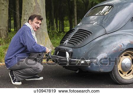 Man fixing vintage car on country road View Large Photo Image Stock Photo - Man fixing vintage car on country road. Fotosearch