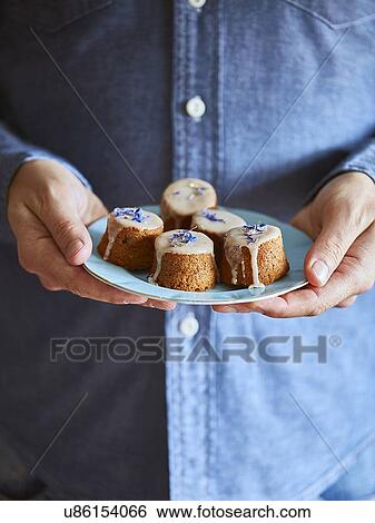 Stock Photograph - Man holding saucer of muffins. Fotosearch