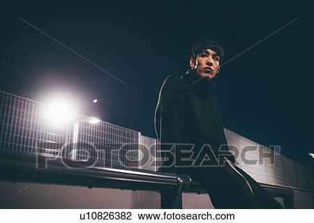 Stock Image - Man leaning against railing waiting, Milan, Italy. Fotosearch