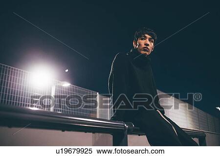 Stock Photography - Man leaning against railing waiting, Milan, Italy. Fotosearch