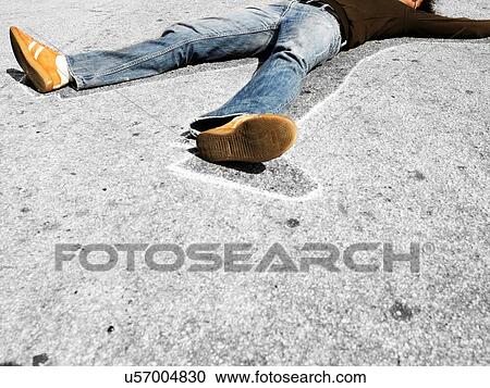 Stock Image - Man lying in dead man chalk outline on concrete. Fotosearch