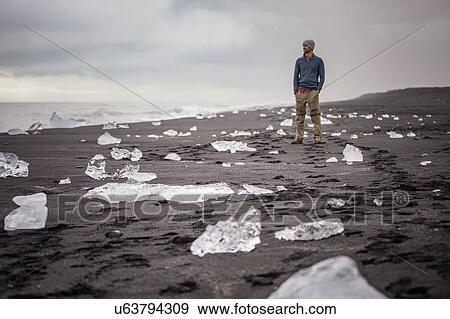 Stock Photo - Man on Jokulsarlon beach (Diamond beach), Iceland. Fotosearch