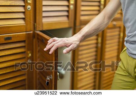 Stock Image - Man opening locker door. Fotosearch