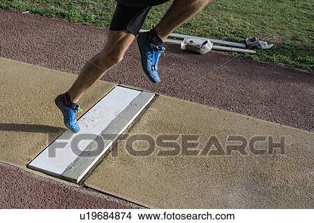 Picture - Man preparing to do long jump, foot on take off plate.. Fotosearch