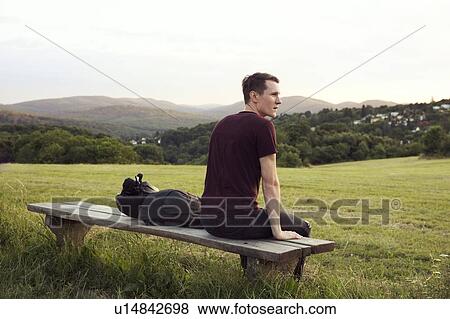 Stock Photo - Man sitting on bench overlooking hills, Wilhelminenberg, Vienna, Austria. Fotosearch