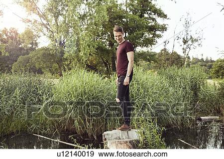 Stock Photo - Man standing on log in pond, Wilhelminenberg, Vienna, Austria. Fotosearch