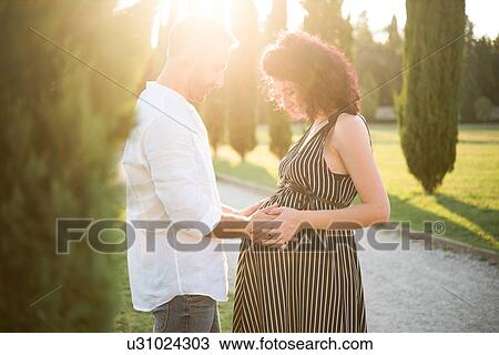 Man touching belly of pregnant wife in park View Large Photo Image Stock Image - Man touching belly of pregnant wife in park. Fotosearch