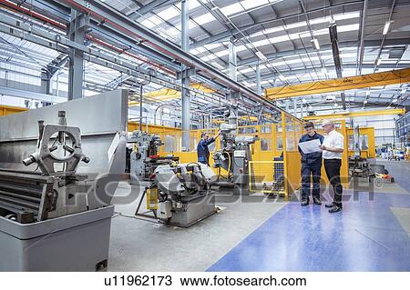 Stock Image - Manager and engineers in electrical engineering factory. Fotosearch