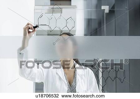 Stock Image - Medical student drawing atoms on glass wall in classroom. Fotosearch
