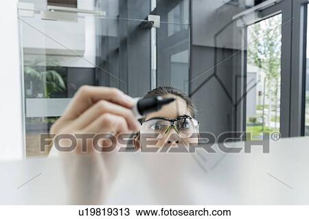 Stock Image - Medical student drawing atoms on glass wall in classroom. Fotosearch