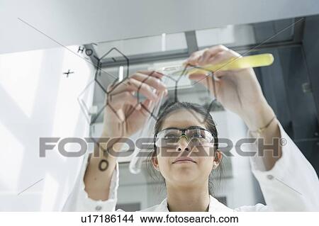 Picture - Medical student pouring liquid into test tube in front of glass wall in classroom. Fotosearch