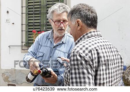 Stock Photo - Men holding wine bottles in discussion, Florence, Italy. Fotosearch